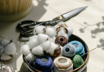 Thread bobbins with scissors and needles placed on table in atelier