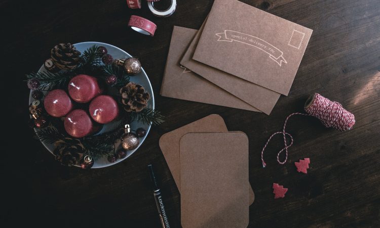 four maroon votive candles on teal ceramic plate surrounded by ornaments